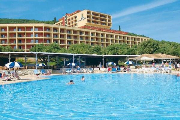 Außenbereich des Atlantica Nissaki Beach Hotels mit Swimmingpool, Sonnenliegen und Gästen.
