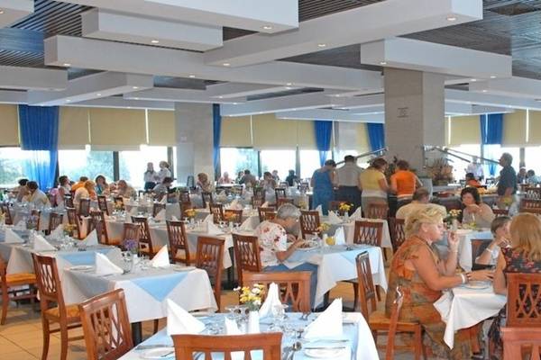 Gäste sitzen in einem großen Restaurant des Atlantica Nissaki Beach Hotels.