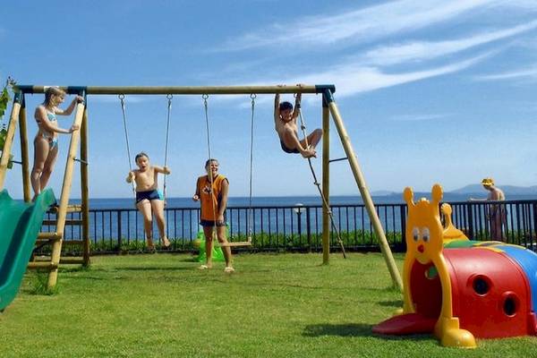 Kinder spielen auf einem Spielplatz im Freien im Atlantica Nissaki Beach Hotel.