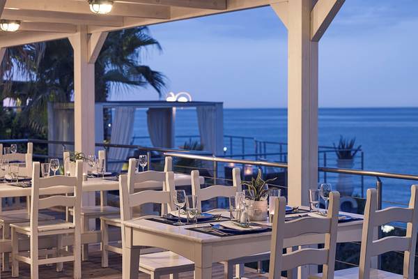 Terrasse des Ikaros Beach Luxury Resort & Spa bei Nacht mit Blick auf das Meer.