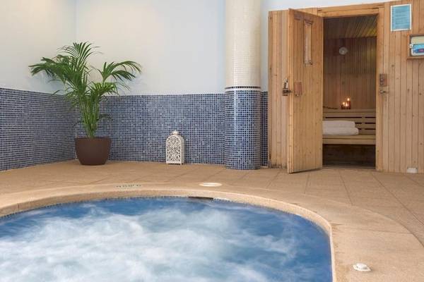 Jacuzzi im Tropic Garden Hotel Apartments mit blauen Fliesen und einer Pflanze.
