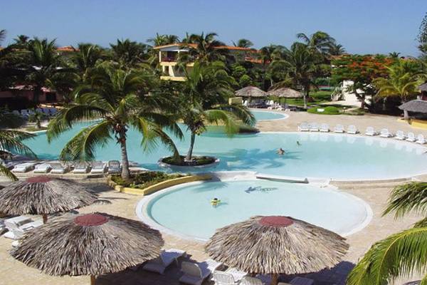 Luftaufnahme des Swimmingpools im Gran Caribe Villa Tortuga Resort mit Palmen und Sonnenliegen.