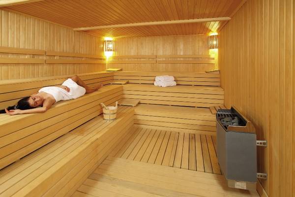 Eine Frau liegt entspannt in einer holzbeplankten Sauna des Radisson Blu Resort & Spa in Cesme.