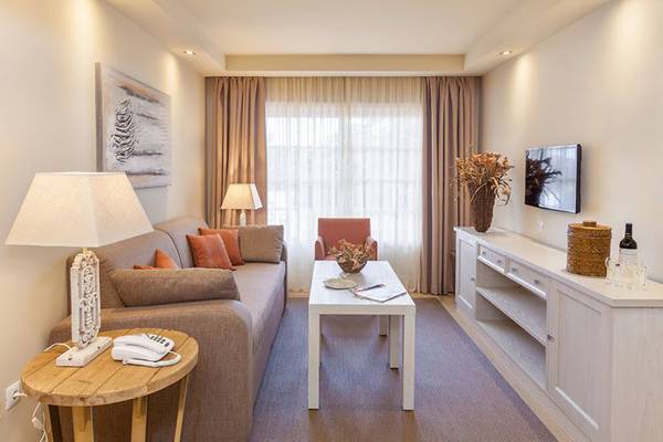Wohnzimmer mit einem Sofa, einem Tisch, einer Lampe, einem Fernseher und einem Teppichboden.