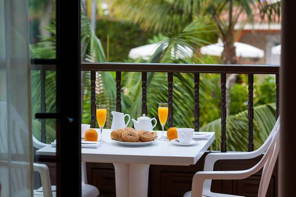 Frühstück auf dem Balkon im Ambassador Apartments mit zwei Gläsern Orangensaft, Brötchen und Orangen.