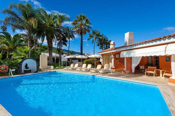 Ein Swimmingpool mit Liegen und Sonnenschirmen im Freien neben dem Ambassador Apartments Hotel.