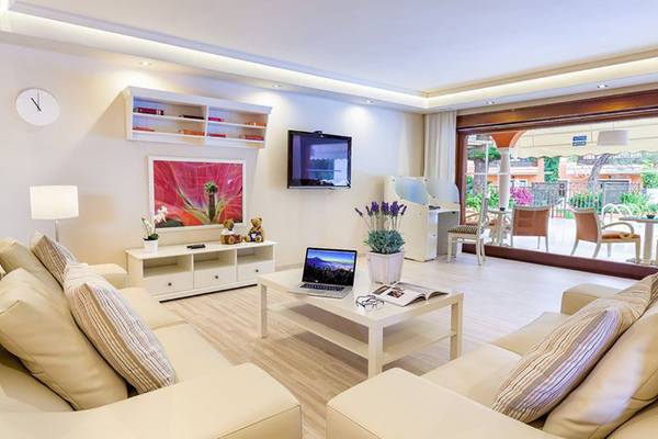 Wohnzimmer im Ambassador Apartments mit weißem Sofa, Fernseher und Laptop auf dem Tisch.