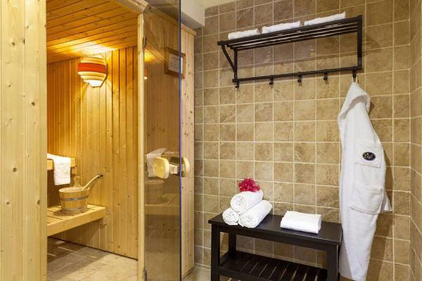 Saunaraum im Ambassador Apartments mit Holzwänden, Glastür und Handtüchern.