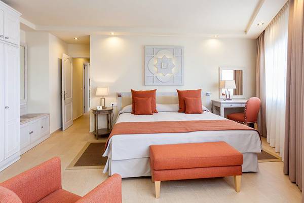 Schlafzimmer im Ambassador Apartments mit großem Bett, orangen Kissen und heller Einrichtung.