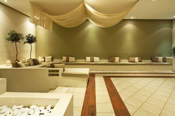 Loungebereich im Kipriotis Hippocrates Hotel mit Sofas, Pflanzen und Fliesenboden.