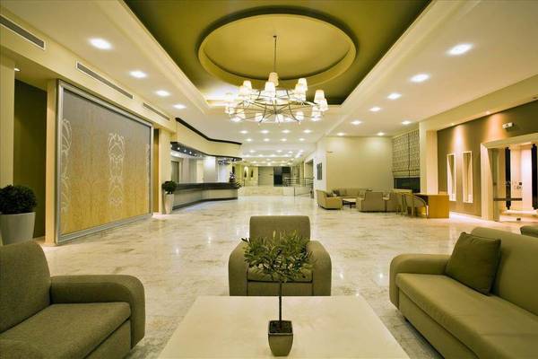 Lobby des Kipriotis Hippocrates Hotels mit Marmorboden, Couchen, und einer Pflanze auf dem Tisch.