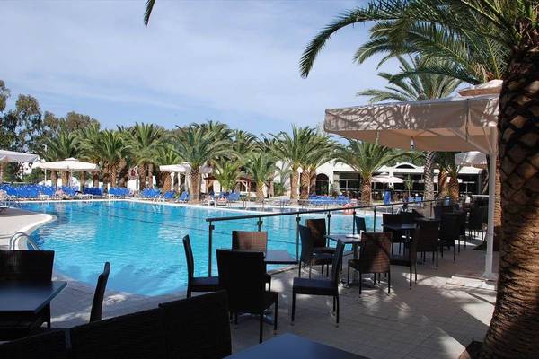 Außenpool-Terrasse des Kipriotis Hippocrates Hotels mit Sonnenschirmen, Tischen und Stühlen.
