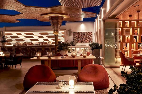 Inneneinrichtung des Myconian Naia Hotels mit Bar, Esstischen und roten Sesseln.