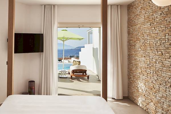 Ein Zimmer im Myconian Naia Hotel mit Blick auf einen Pool und die Küste.
