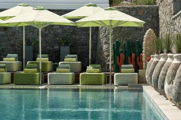 Poolbereich mit Loungemöbeln und großen grünen Sonnenschirmen im Myconian Naia Hotel.