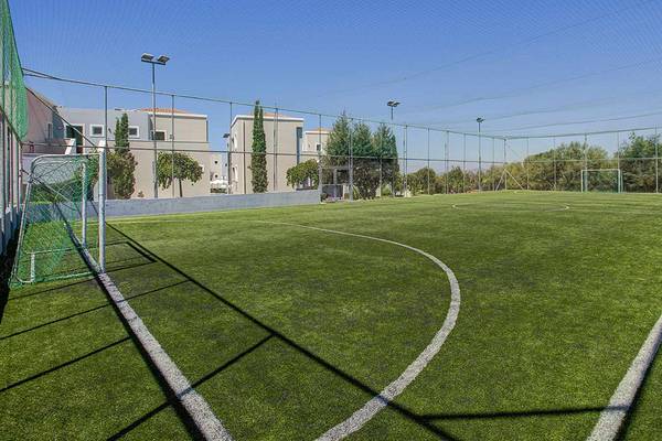Sportplatz des Atlantica Marmari Palace Hotels mit grünem Kunstrasen und Umzäunung.