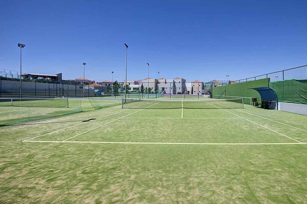 Tennisplatz im Atlantica Marmari Palace mit leeren Spielfeldern und umliegenden Gebäuden.