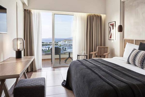 Hotelzimmer des Atlantica Marmari Palace mit Blick auf den Ozean, inklusive Bett, Schreibtisch und Balkon.