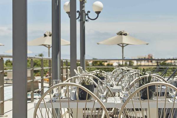 Dachterrasse des Atlantica Marmari Palace mit gedeckten Tischen und Sonnenschirmen.