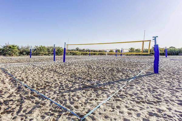 Volleyballfelder auf einem Sandstrand mit blauen Netzen und Pfosten.