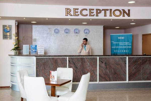Empfangsbereich des Sentido Golden Star Hotels mit einem Mitarbeiter am Telefon und einer Willkommensanzeige.