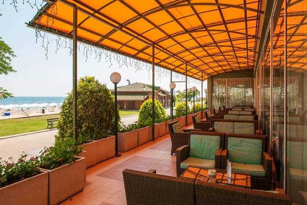 Terrasse des Sentido Golden Star Hotels mit Blick auf das Meer und Stühle unter einem orangefarbenen Baldachin.