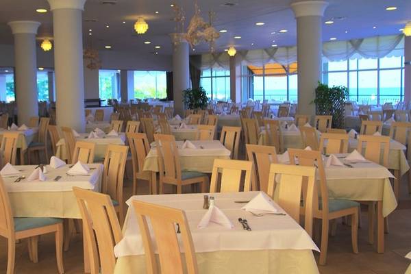 Innenansicht des Restaurants im Sentido Golden Star Hotel mit vielen gedeckten Tischen und Blick auf das Meer.