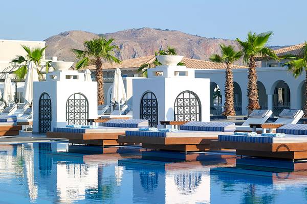Außenpool-Loungebereich des Anemos Luxury Grand Resort mit Liegen und Palmen
