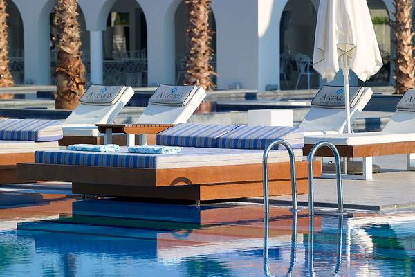 Loungebereich am Pool im Anemos Luxury Grand Resort mit Sonnenliegen und Schirmen
