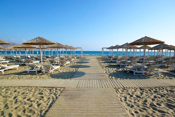 Strand des Anemos Luxury Grand Resort mit Liegen und Sonnenschirmen