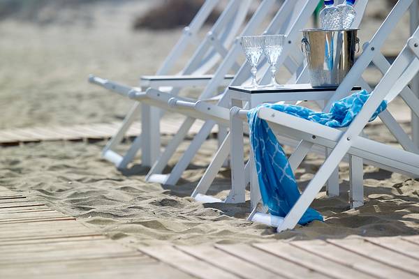 Weiße Stühle am Strand mit Eiskühler und Gläsern im Anemos Luxury Grand Resort