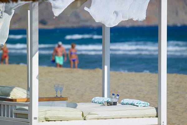 Strandbett am Anemos Luxury Grand Resort mit Blick auf das Meer und Personen am Strand.