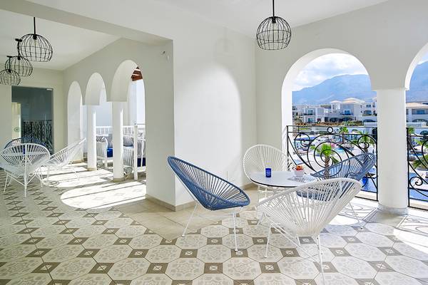 Anemos Luxury Grand Resort Balkon Sitzbereich mit modernen weißen Möbeln und Blick auf das Hotelgelände.