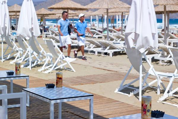 Besucher des Anemos Luxury Grand Resort gehen am Strand entlang.