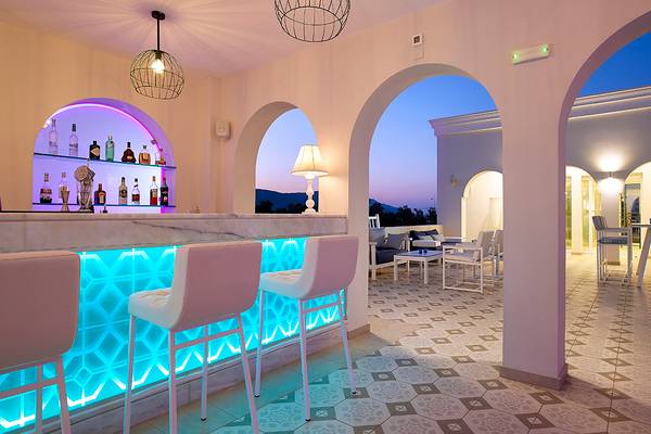 Bar im Anemos Luxury Grand Resort mit blau beleuchteter Theke und weißen Stühlen.