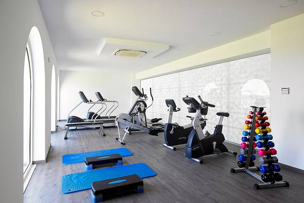 Fitnesscenter im Anemos Luxury Grand Resort mit verschiedenen Trainingsgeräten und Gewichten.