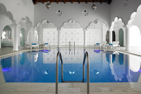 Innenpool im Anemos Luxury Grand Resort mit weißen Wänden und blauem Wasser.