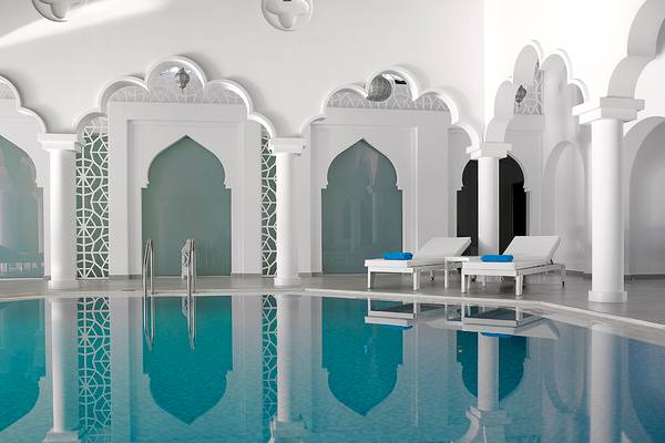 Pool-Lounge-Bereich im Anemos Luxury Grand Resort mit weißen Möbeln und blauen Handtüchern.