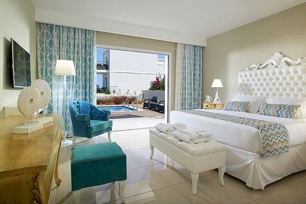 Schlafzimmer im Anemos Luxury Grand Resort mit Blick auf den Pool.