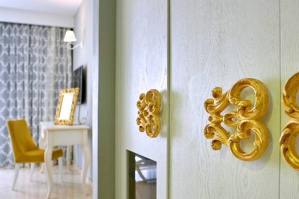 Innenansicht des Anemos Luxury Grand Resorts mit weißen Wänden, goldenen Türklinken und einem weißen Tisch mit Spiegel.