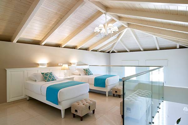 Schlafzimmer im Anemos Luxury Grand Resort mit zwei Betten, weißen Wänden und Holzdecke.