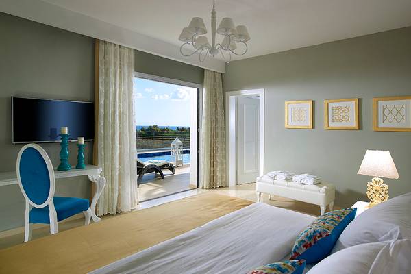 Schlafzimmer im Anemos Luxury Grand Resort mit Blick auf den Pool.