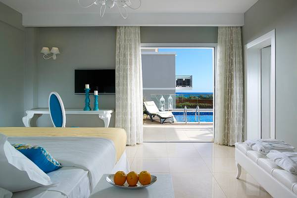 Schlafzimmer im Anemos Luxury Grand Resort mit Ausblick auf den Pool.