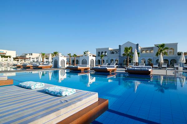 Poolbereich des Anemos Luxury Grand Resort mit Liegen und weißen Gebäuden