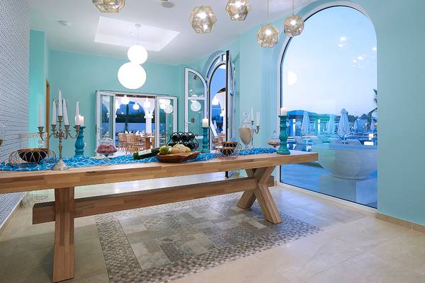 Innenraum des Anemos Luxury Grand Resort mit einem langen Tisch und blauen Dekorationen.