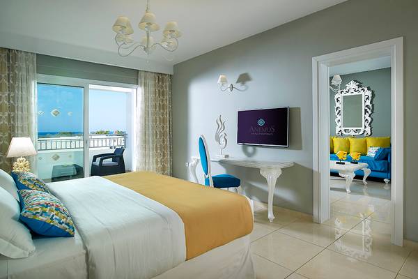 Suite-Zimmer im Anemos Luxury Grand Resort mit Meerblick, modernen Möbeln und einem blauen Sofa.