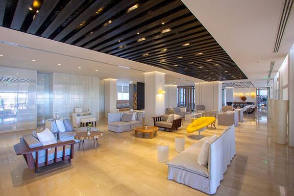Lobby des Cavo Maris Beach Hotels mit modernen Möbeln und holzigen Decken.