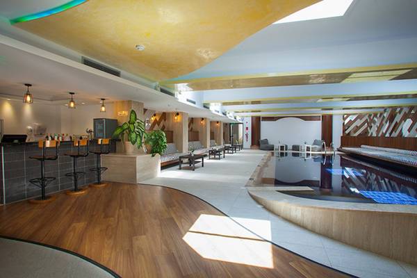 Innenbereich des Cavo Maris Beach Hotels mit Bar, Möbeln und Swimmingpool.