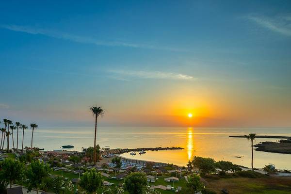 Sonnenuntergang am Strand des Cavo Maris Beach Hotels mit Blick auf das Meer und die Palmen