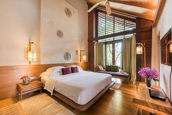 Schlafzimmer im Tubkaak Krabi Boutique Resort mit einem großen Bett, Wandlampen und einer Aussicht auf den Garten.